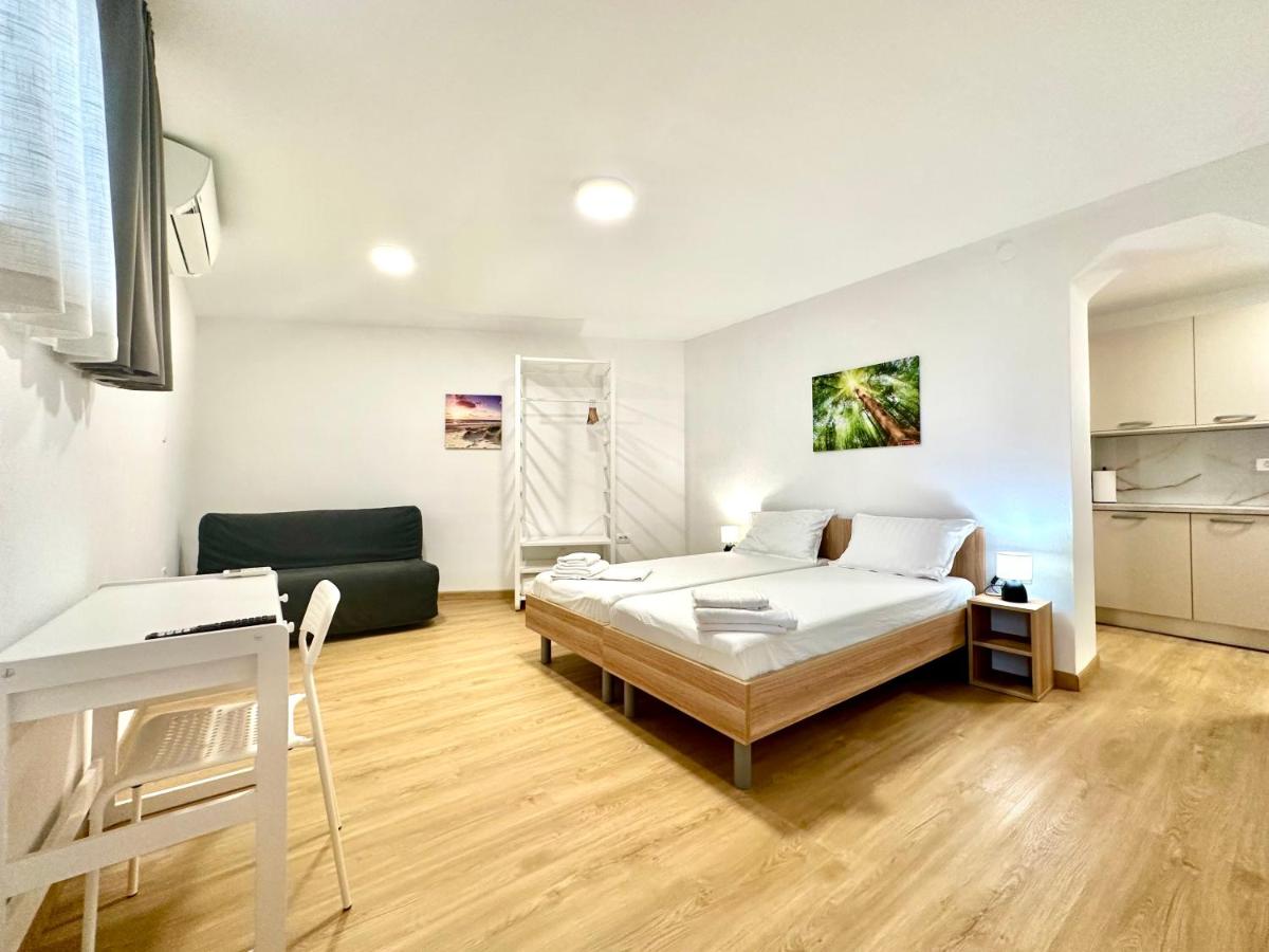 Svetel, prostoren apartma s posteljo, kavčem in kuhinjskim kotom